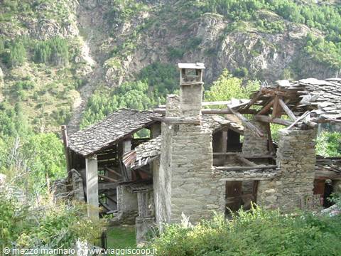 Stone house ruins with collapsed roof, green birch trees on mountain