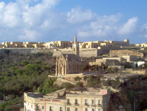 Gothic Revival limestone church beneath the fortified citadel walls of Victoria