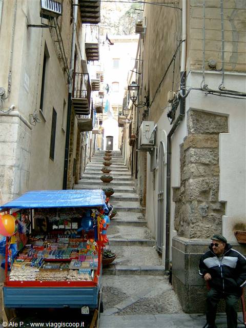 Stone stairway alley in Cefalù, sweets cart and seated old man