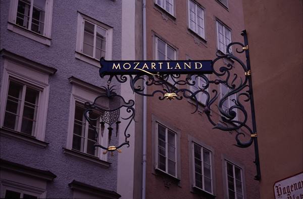 Wrought iron "Mozartland" sign between pastel facades, Salzburg