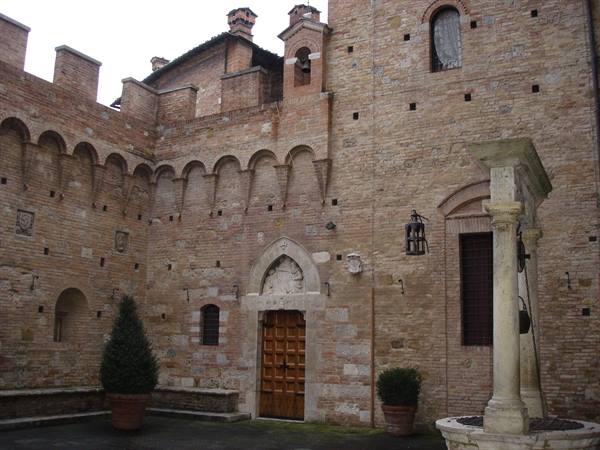 Brick courtyard with stone well and wooden door in Certaldo