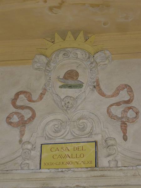 Stucco crest with crown and painted snail, yellow plaque Casa del Cavallo