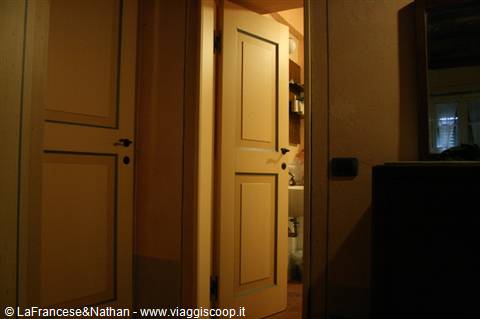 Yellow wooden door ajar onto a lit bathroom in a dark house