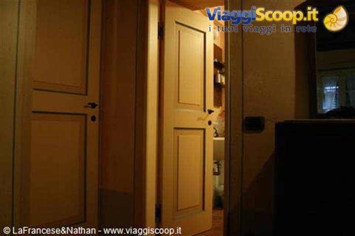 Yellow wooden door ajar onto a lit bathroom in a dark house