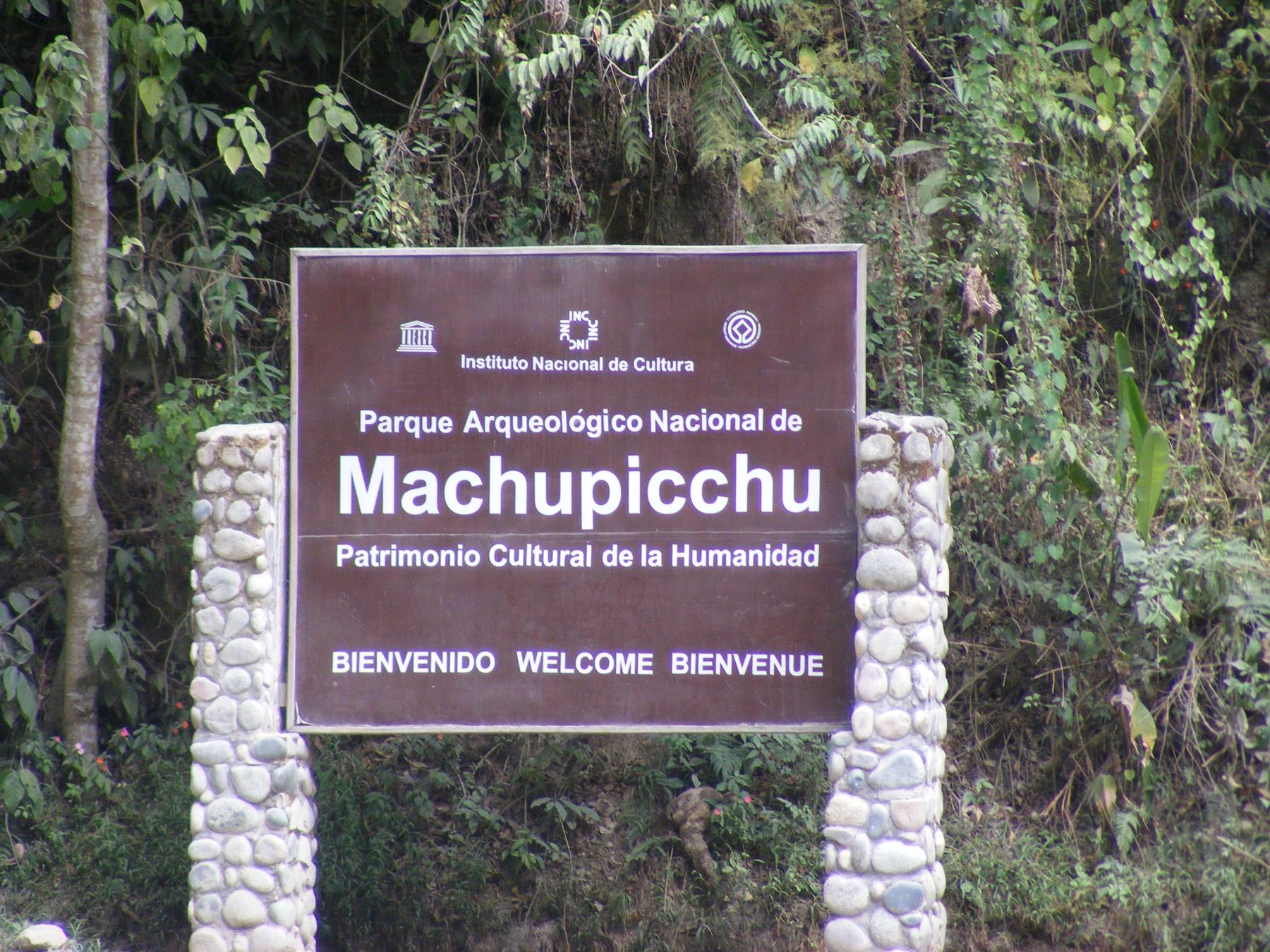 Brown entrance sign of Machupicchu National Archaeological Park surrounded by greenery