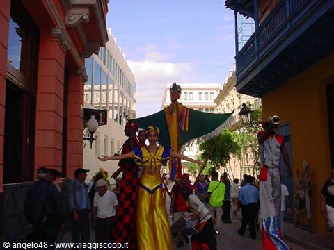 Stilt performers in yellow and red costumes parading in Old Havana