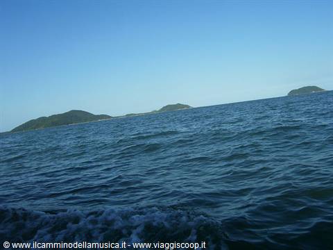 Green islands on the horizon, blue waves with foam up close