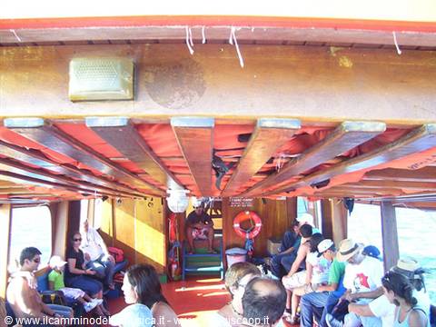 Passengers under red wooden ferry roof, lifebuoy hanging