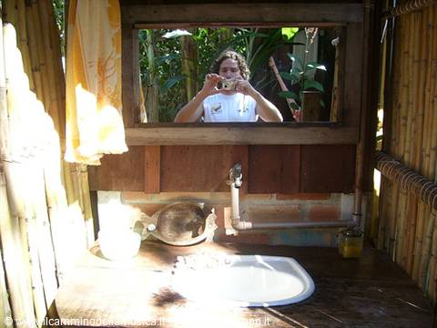 Man photographing himself in mirror above sink inside bamboo bathroom