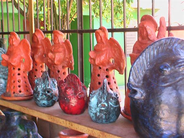 Glazed ceramic figurines and fish lined up on a wooden shelf