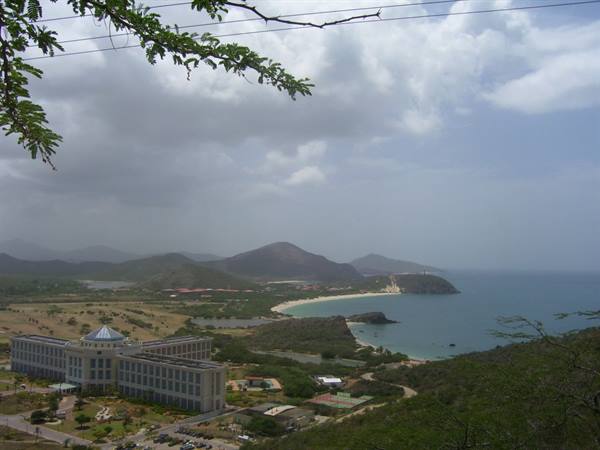 Large hotel with blue dome overlooking the bay, sandy beach and green hills