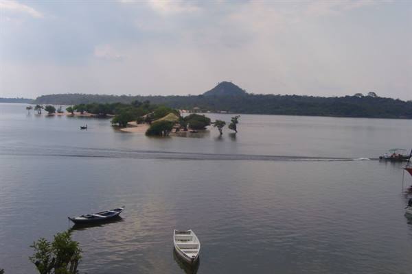 Boats on the wide river with sandy islands and forested hill behind