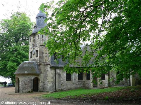 Old stone chapel with tower, nestled among lush green trees