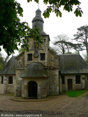 Stone chapel with dome and slender bell tower among green trees