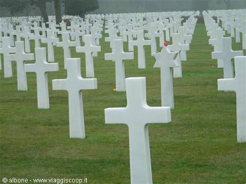 Rows of white marble crosses on green lawns, American military cemetery in the fog