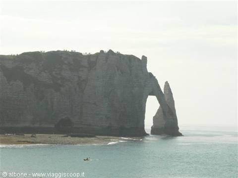 Étretat's natural arch in the chalk cliff, with a kayak on the sea