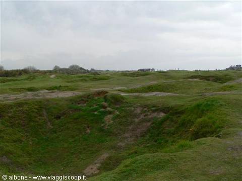 Grass-covered bomb craters under a cloudy overcast sky