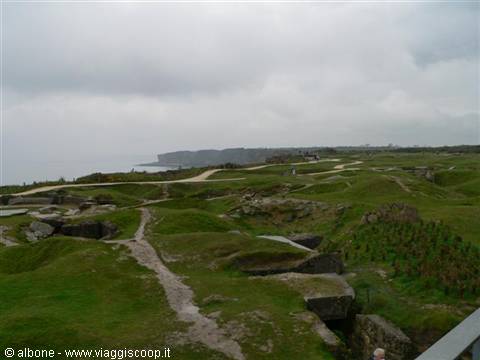 Concrete bunkers among grassy craters at Pointe du Hoc, grey sky