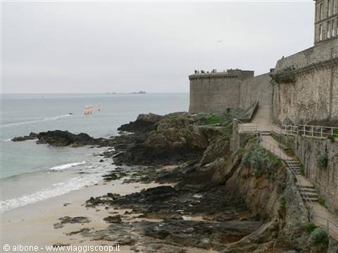 Saint-Malo ramparts above the rocky shore, sailboats offshore, cloudy light