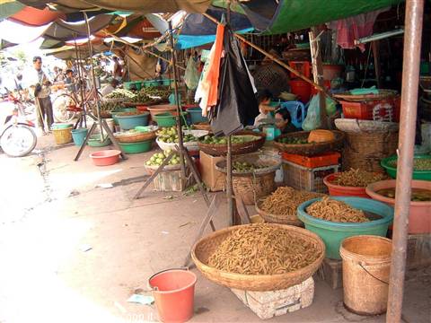Open-air market stall with baskets of grains and colorful fruit
