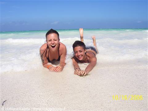 Two girls lying on white sand among turquoise waves