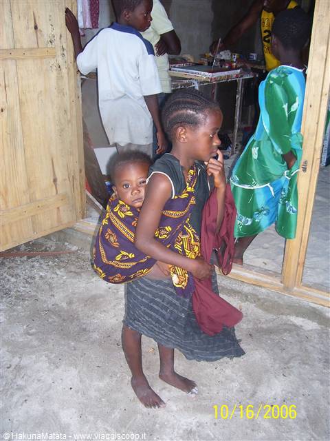 Young girl carrying her baby brother on her back in a courtyard