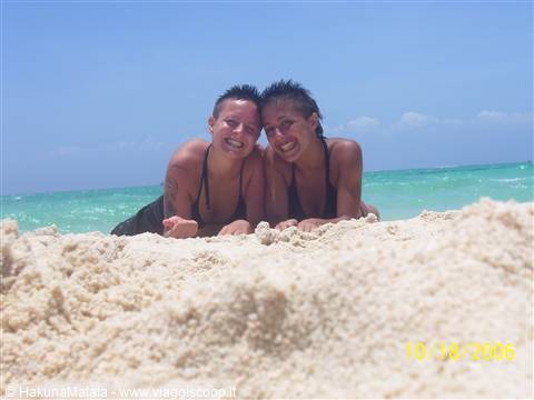 Two girls lying on white sand, turquoise sea and blue sky