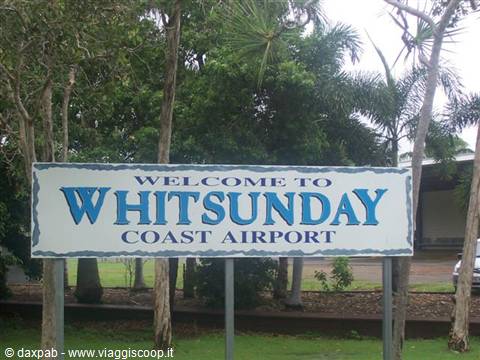 White welcome sign of Whitsunday Coast Airport among palm trees
