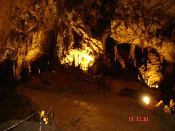Illuminated cave with golden stalactites and metal walkway