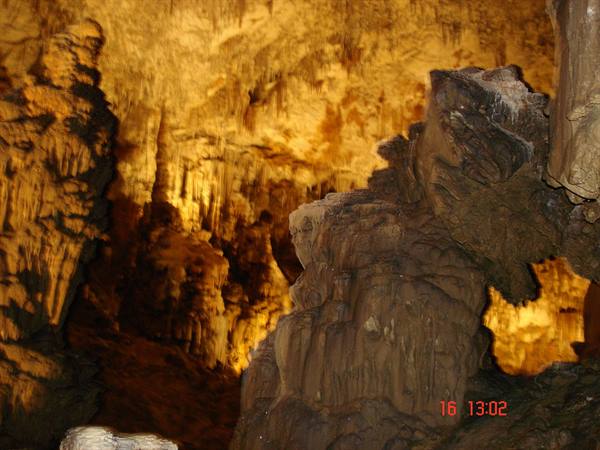 Limestone stalactites and stalagmites lit by golden light inside a cave