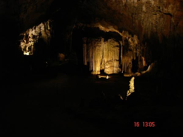 Cave with stalactites and stalagmites lit by golden light