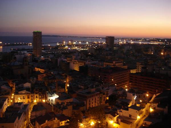 Alicante at dusk: lit buildings, high-rise, harbor and sea in the distance