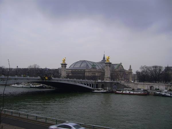 Pont Alexandre III spans the Seine, with the Grand Palais under a cloudy sky