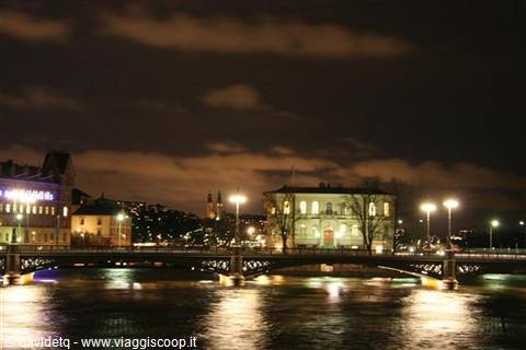 Illuminated bridge over water in Stockholm, night buildings and reflections