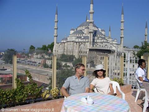 Couple seated at a rooftop café table in front of the Blue Mosque