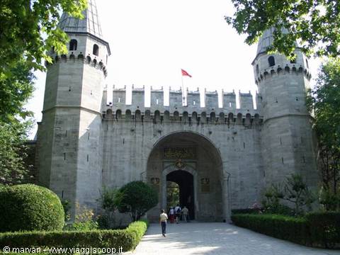 Gate of Salutations at Topkapi Palace, stone towers with Turkish flag, visitors beneath the arch