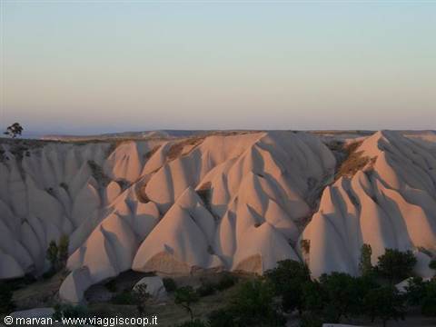 Pink rock formations of Cappadocia glowing under dawn sky