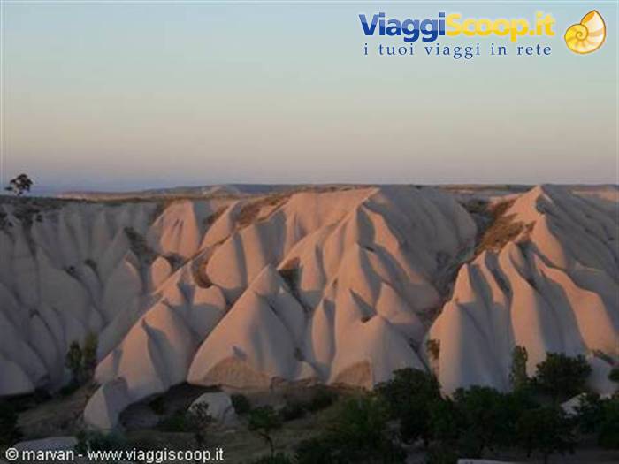 Pink rock formations of Cappadocia glowing under dawn sky