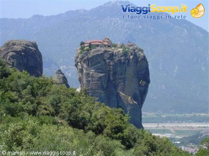 Monastery atop a rock pillar in Meteora, greenery and mountains behind