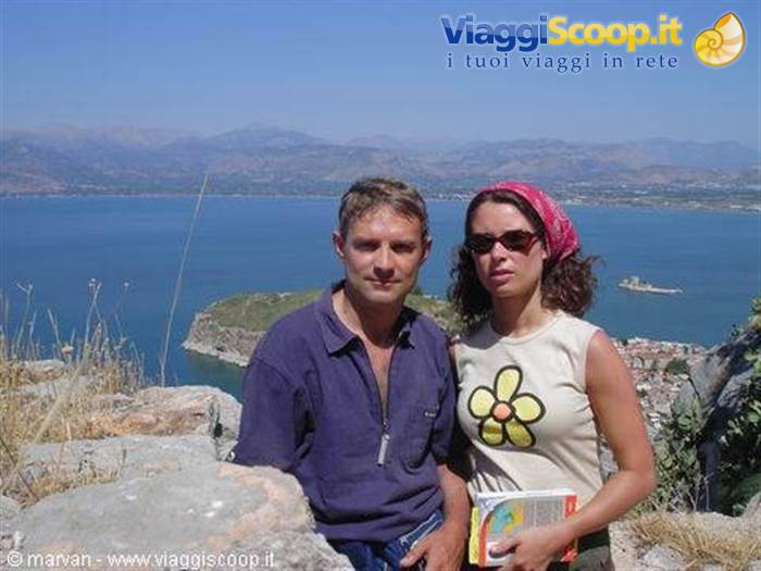 Tourist couple above Nafplio, Bourtzi fortress on the sea behind
