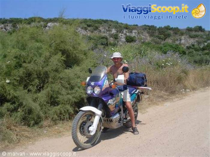 Loaded adventure motorcycle on a dirt road among Mediterranean shrubs