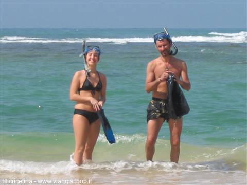 Two snorkelers with masks and fins standing in turquoise sea water