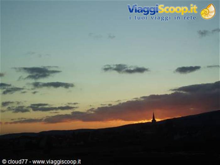 Church spire silhouette on the hill, orange sky with dark clouds