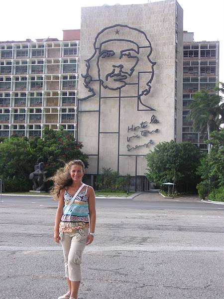Smiling tourist in front of the Che Guevara mural at Plaza de la Revolución, Havana