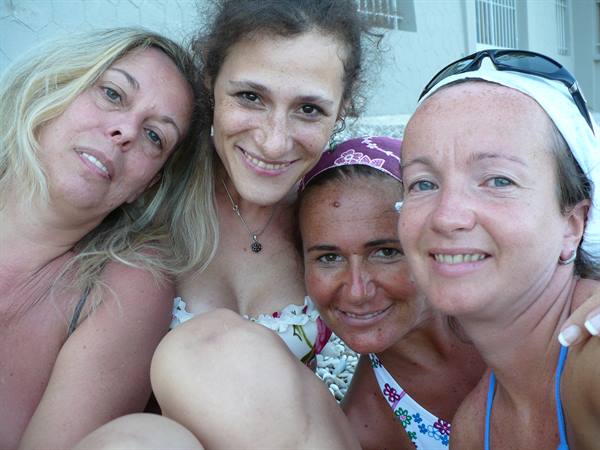 Four smiling friends in swimsuits by a pool