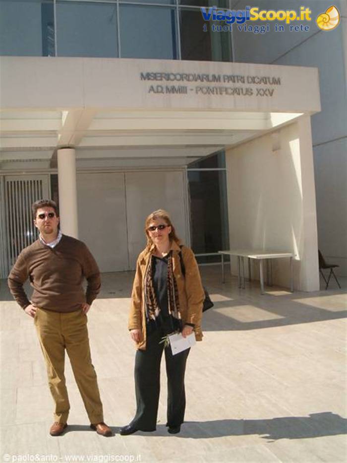 Couple in sunglasses beneath the modern Misericordiarum Pius Dicatum entrance