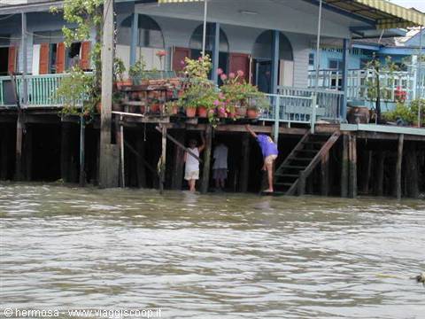 Stilt houses over the water, people on wooden stairs, potted flowers