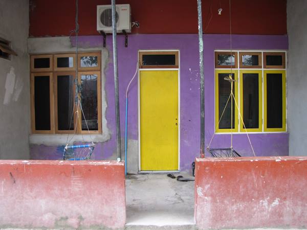Purple facade with yellow door, air conditioner and swings hanging on the porch