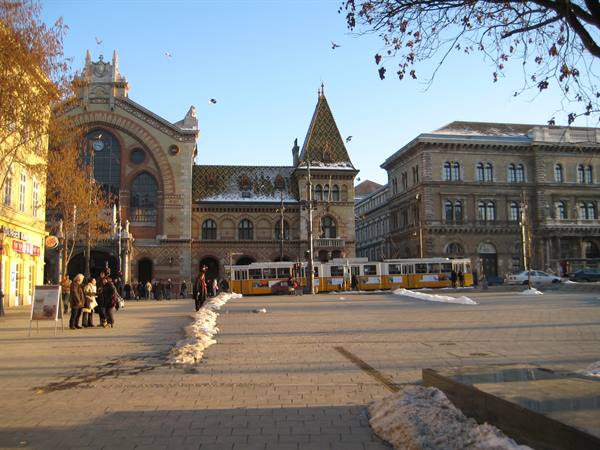 Yellow tram in front of Budapest Great Market Hall, snow along the edges
