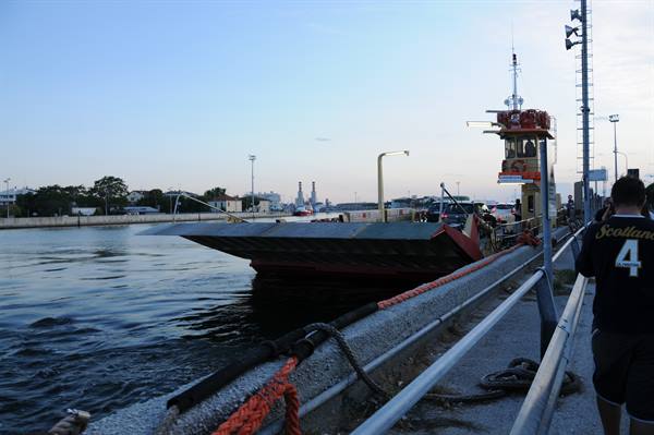 Ferry with lowered ramp at the quay, passengers waiting under evening lights